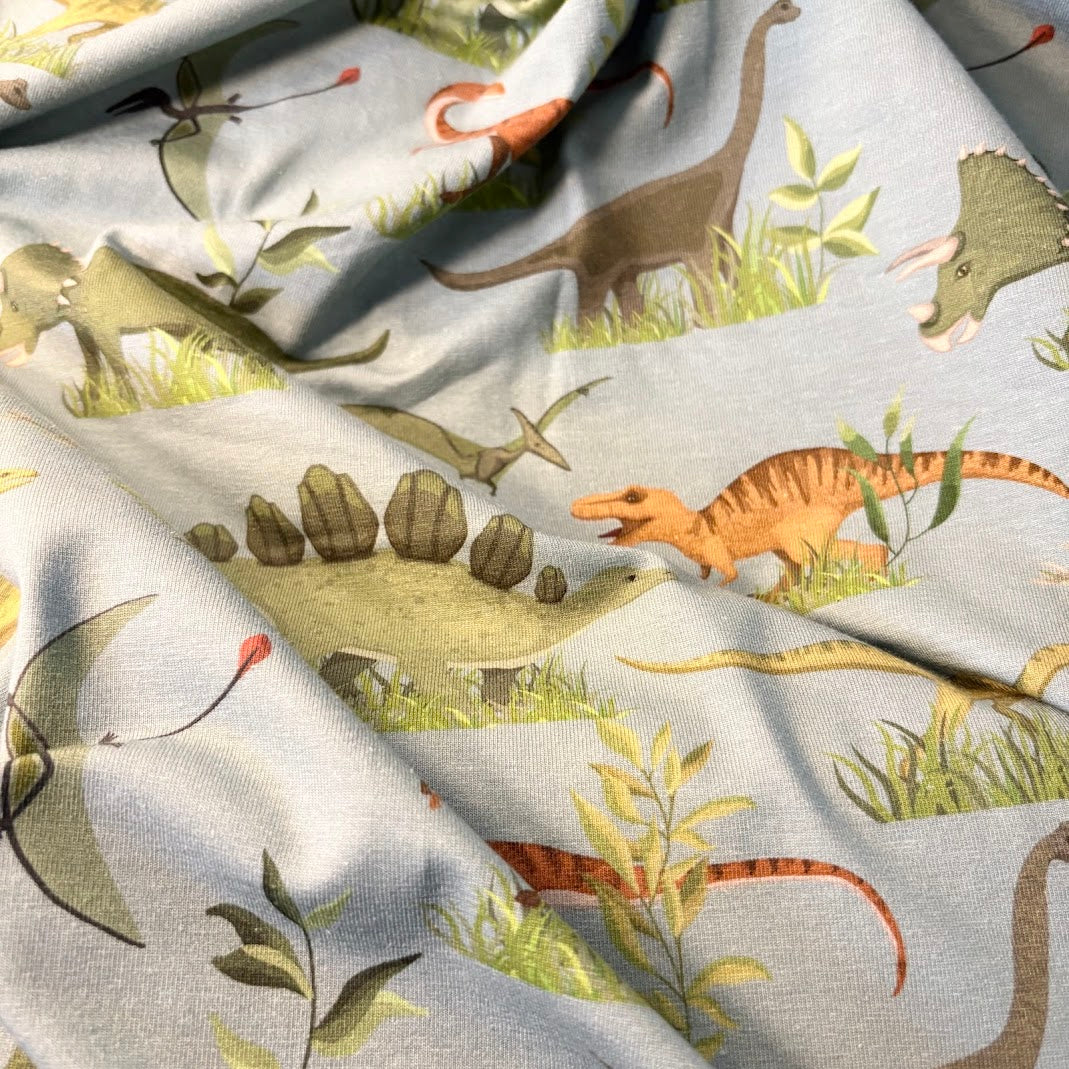 Jerseytyg Dino med tecknade dinosaurier på grön botten, metervara ca 150 cm brett