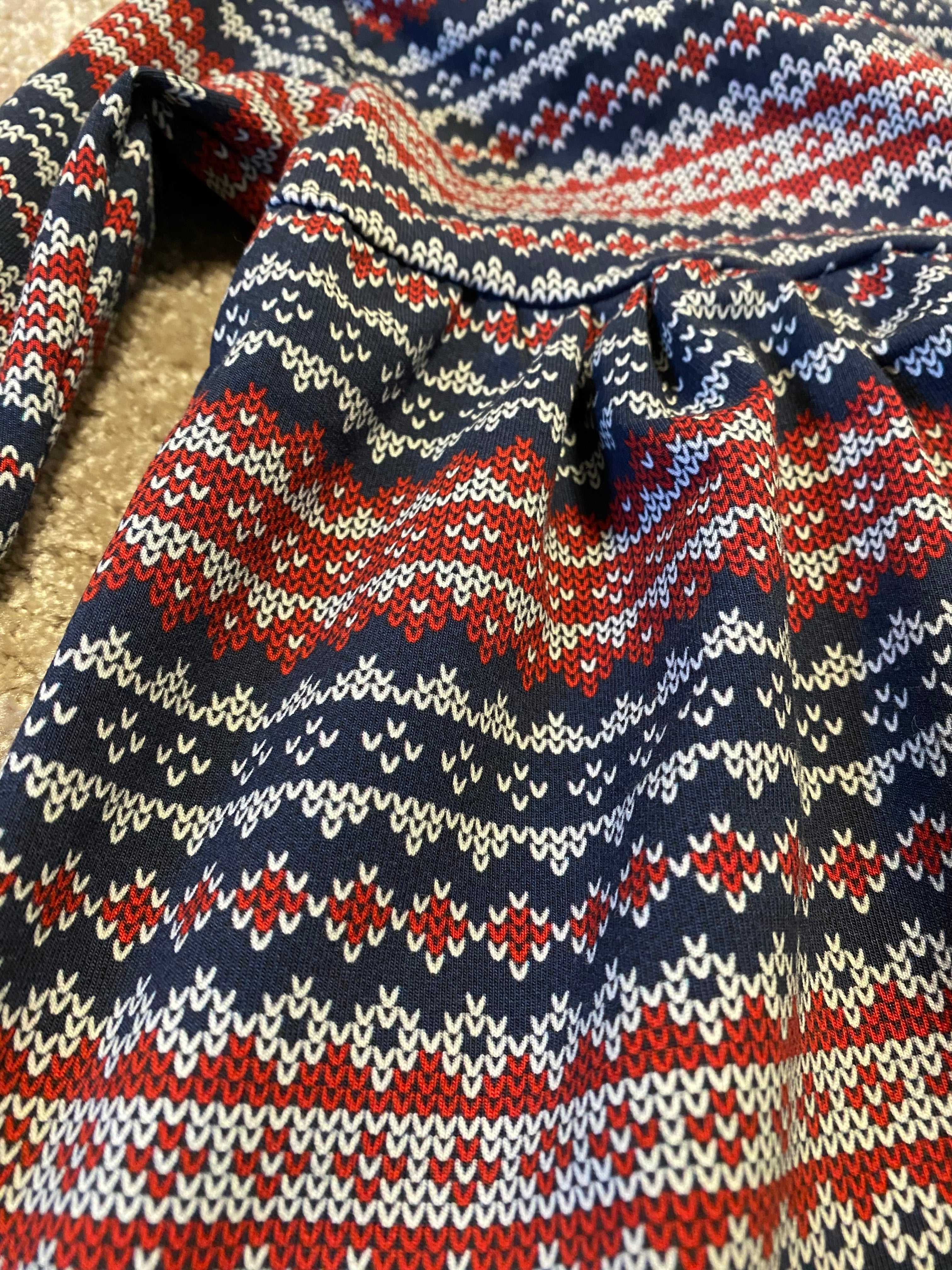 Barnklänning i stickat mönster, detaljbild på trycket.