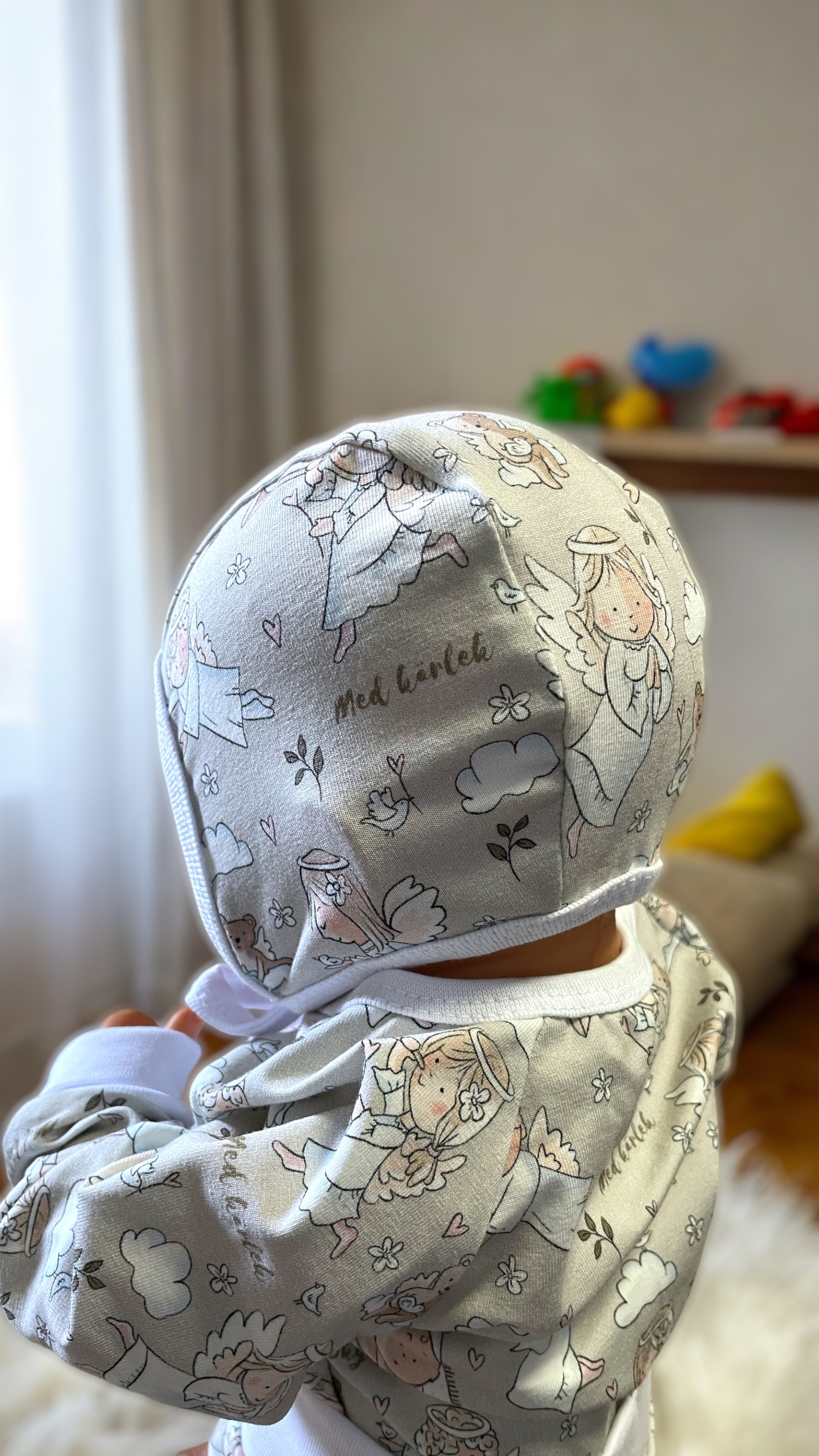 Hjälmmössa för baby i skyddsängelmönster med knyt under hakan
