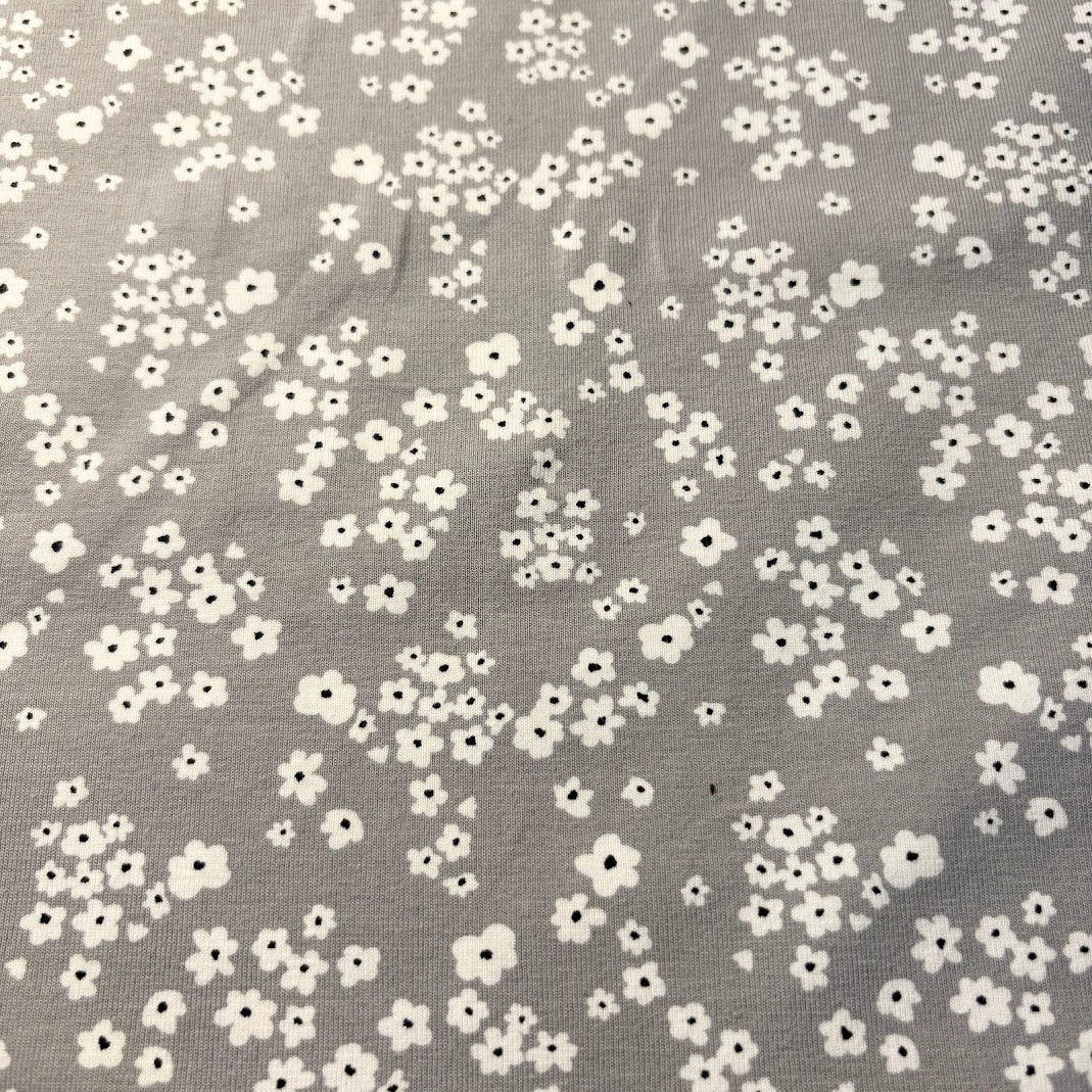 Jerseytyg med små vita blommor mot grått, metervara ca 150 cm brett